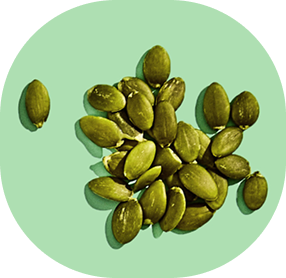 A pile of green pumpkin seeds on a light green background.