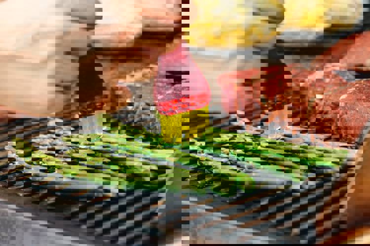 a person is cooking asparagus on a grill