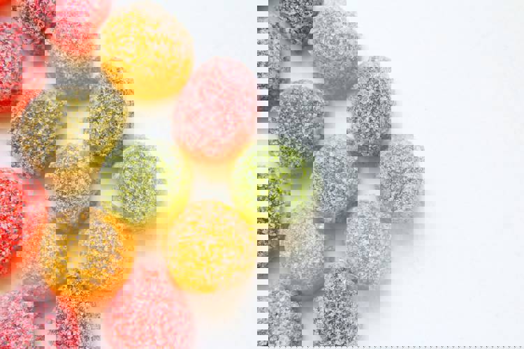a bunch of different colored gummy candies on a white surface